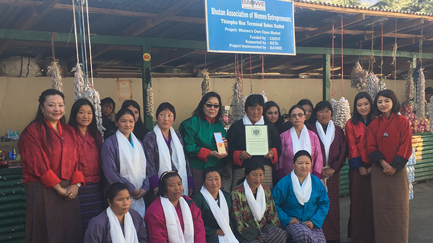 A group of 17 women street vendors at the Thimphu bus terminal sales outlet, with Damchae standing in the middle of them