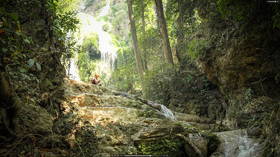 A visitor of the Green Jungle Park near a waterfall