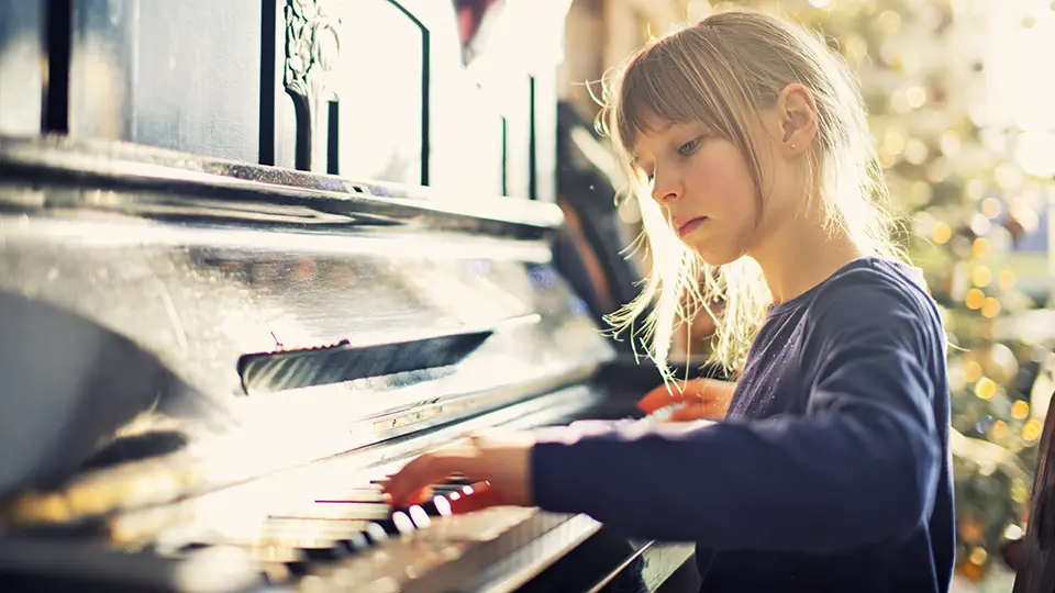 A young girl having a go at a piano