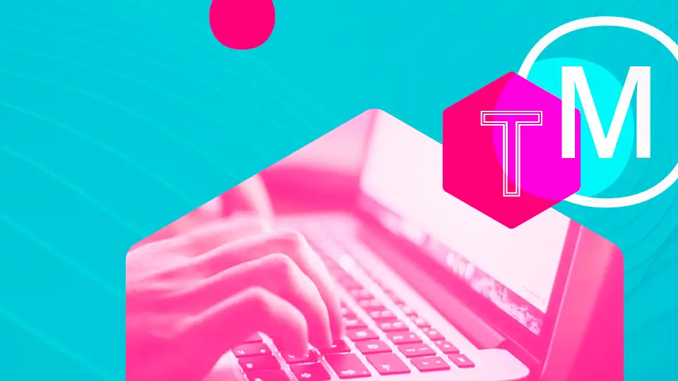 Close-up of hands typing on a laptop, tinted vivid pink against turquoise