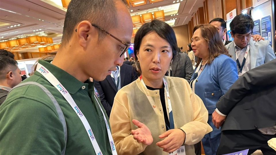 Ms. Kim Eunji, Technical Expert, explains WIPO Global IP Services to a visitor at the WIPO booth