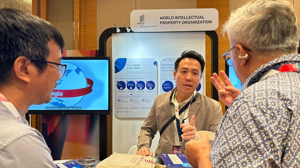 Mr. Marvin Jareth Chia from WIPO explains WIPO tools and services to two visitors at the WIPO booth