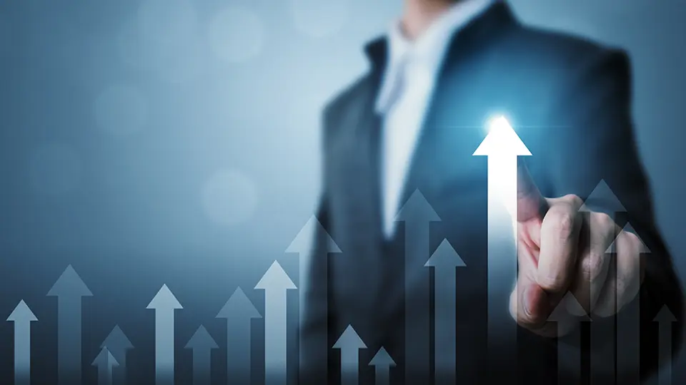 A businessperson in a dark suit gestures toward a glowing upward arrow amid rising graphics